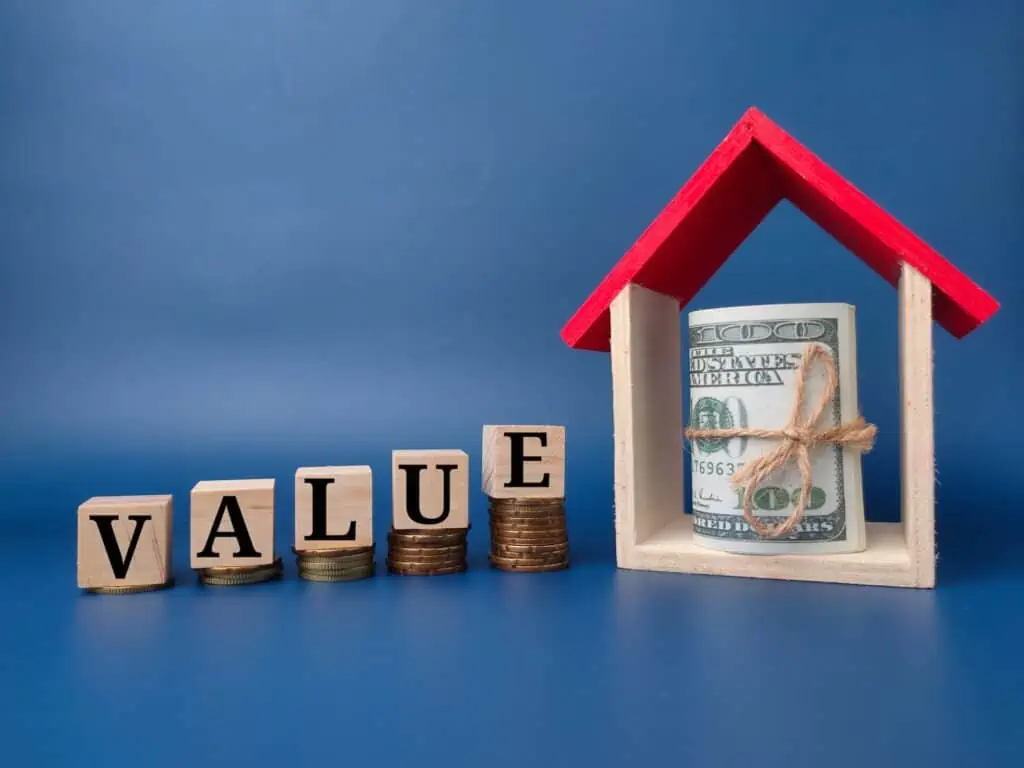 Toy house and banknote with the word VALUE on a blue background.